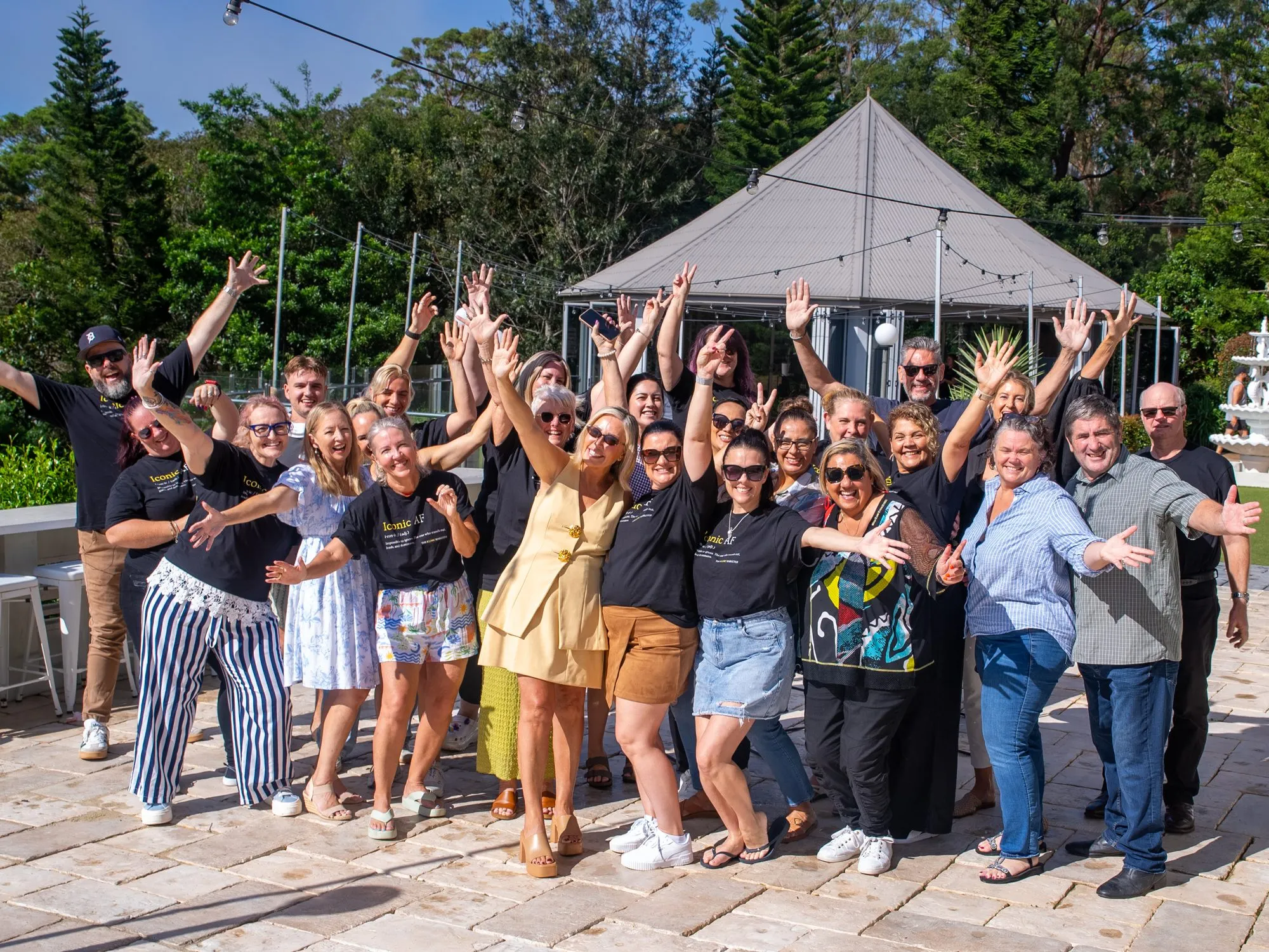 A large group celebrating outdoors at the end of a live experience, arms in the air