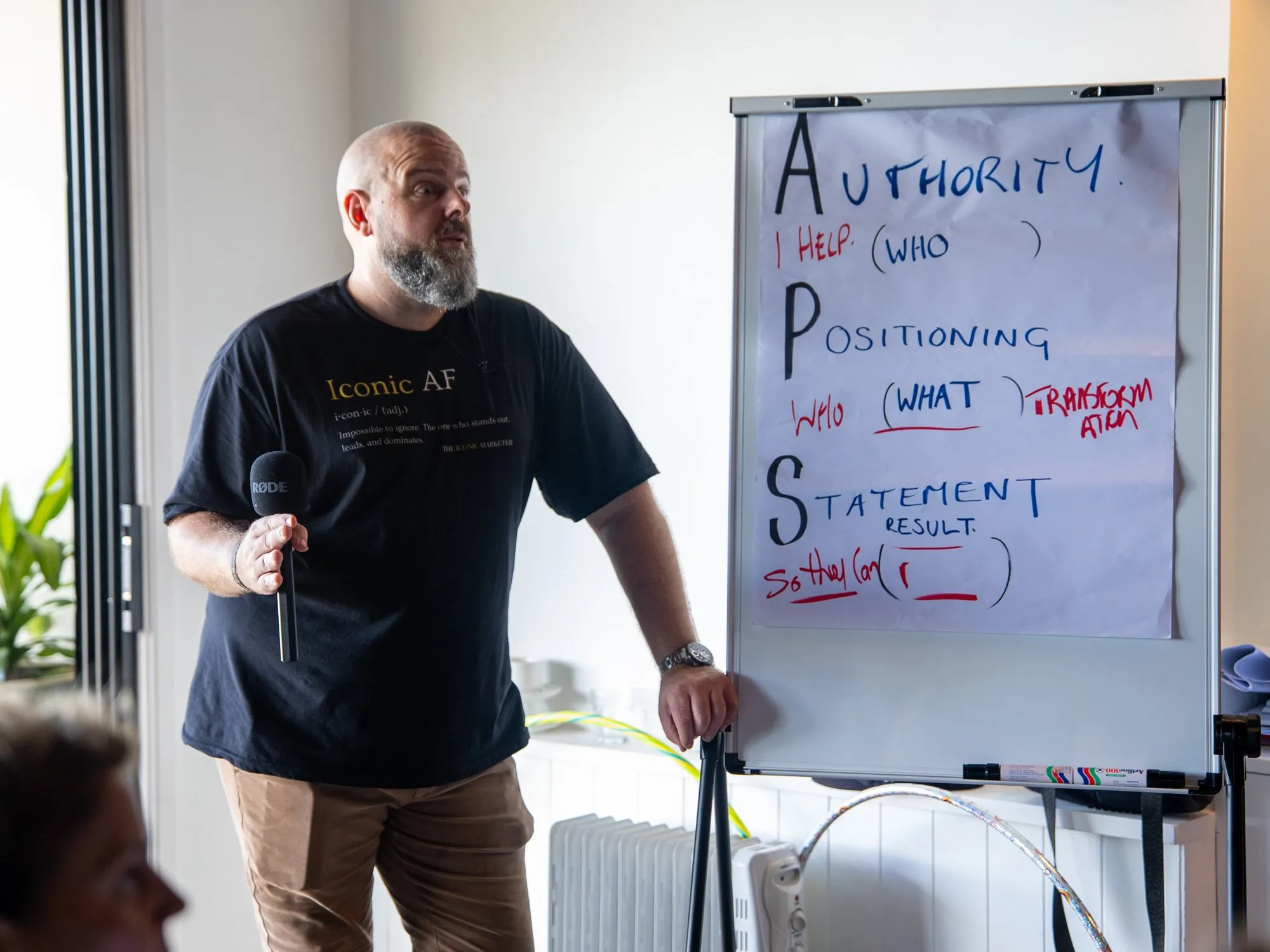 Brett leading a workshop with a handheld mic beside a flipchart
